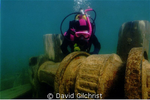 Young diver examines the windlass of the Schooner 'Sweeps... by David Gilchrist 